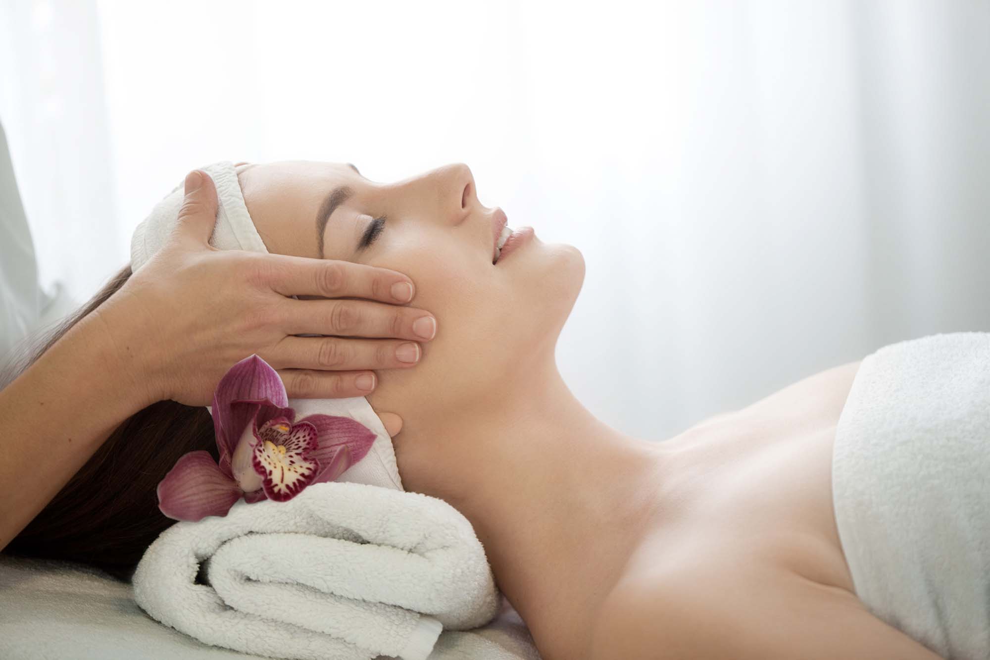Spa salon: Young Beautiful Woman Having Facial Massage with Orchid